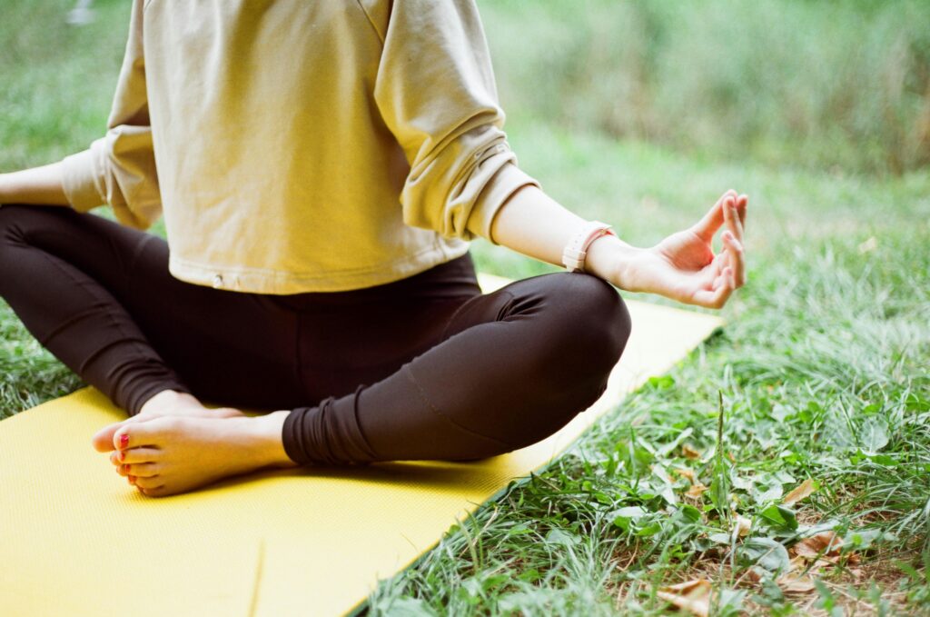 Woman practicing mindfulness in the grass on a yoga mat.