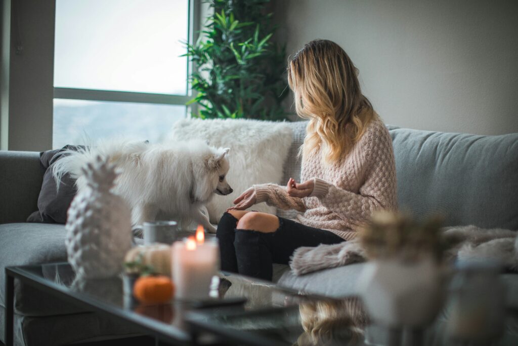 Woman and her dog sitting on the couch with candles in front of them.