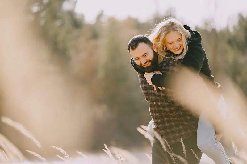 Woman on boyfriend's back, both smiling and happy.