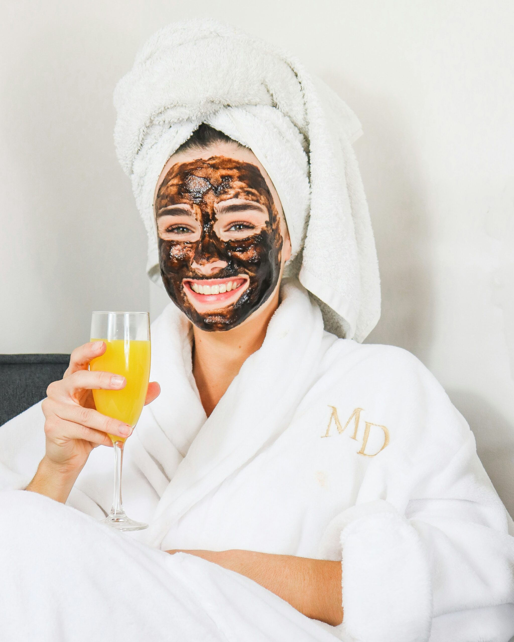 Woman doing a face mask in a robe and towel.