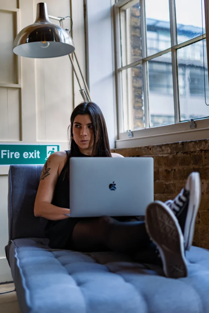 Woman working while laying on couch.