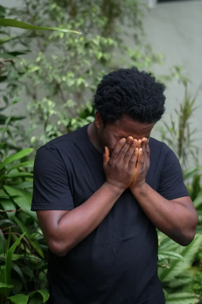 Man outside with his face in his hands.