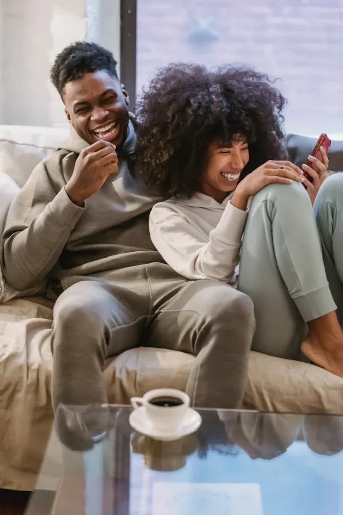 Couple laughing on the couch together.