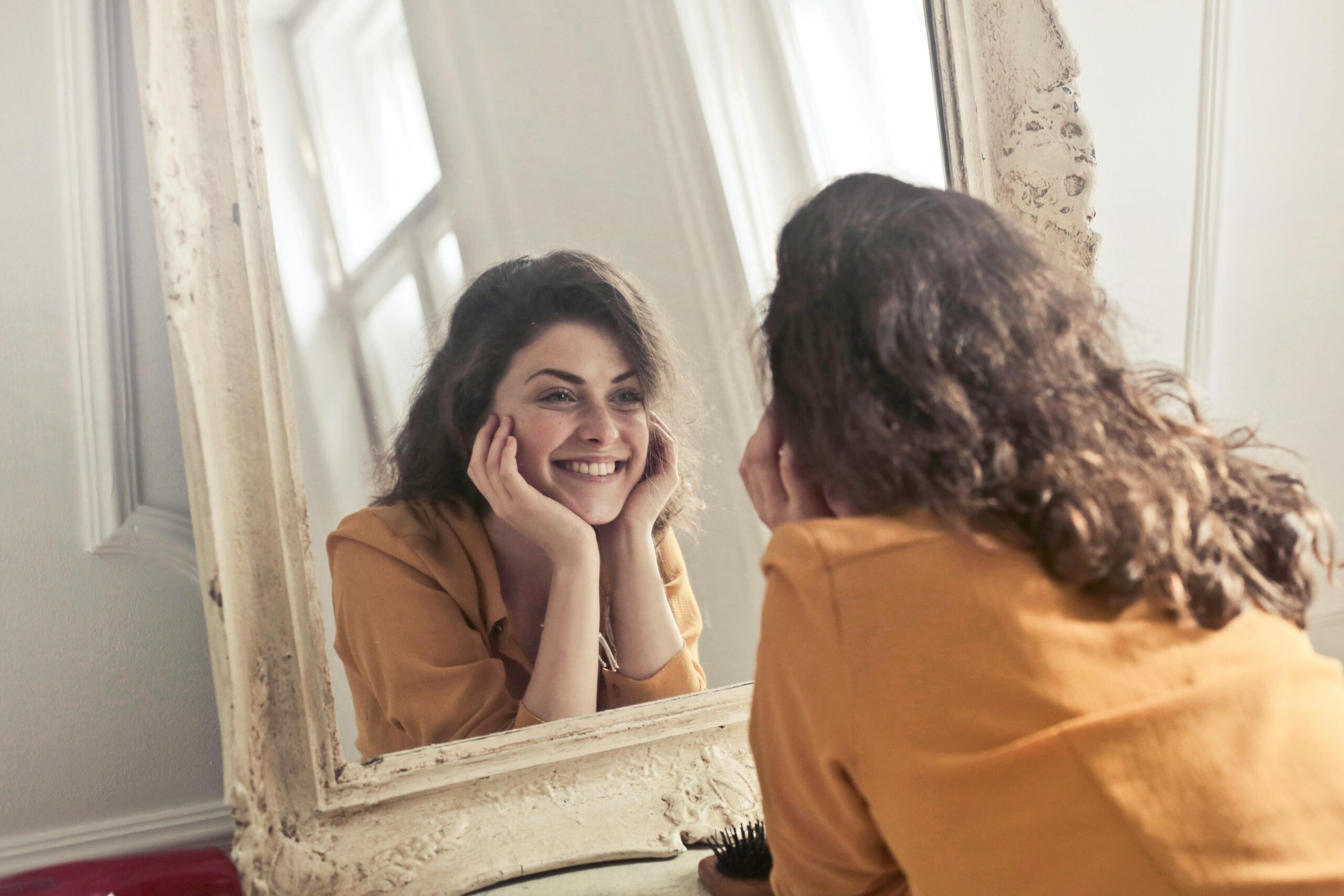 Woman smiling at herself in the mirror.