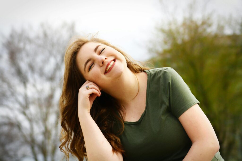 Woman smiling big with her eyes closed outside.