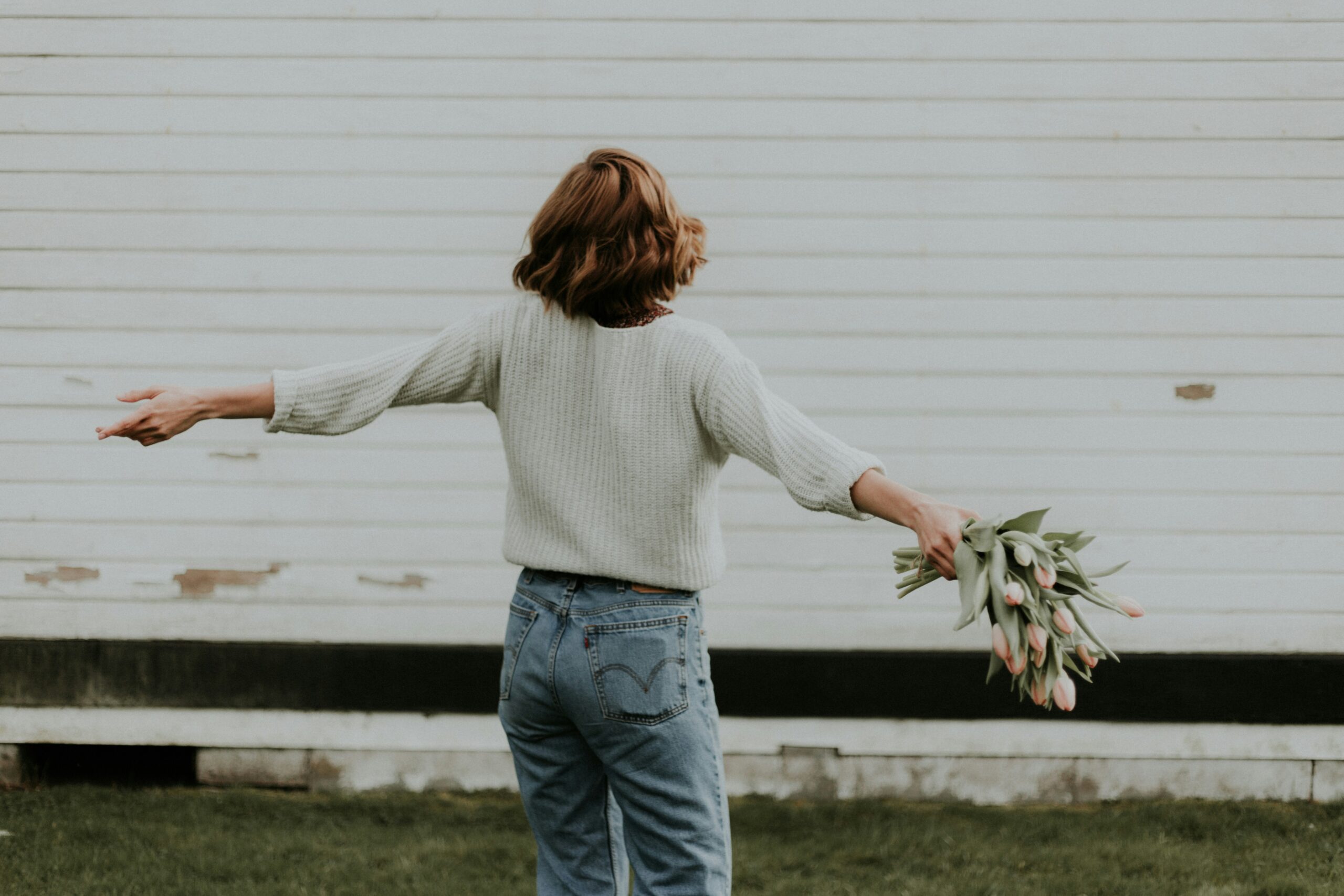 Woman dancing outside holding flowers.