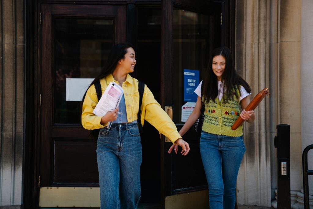 Two girls smiling and walking out of class together.