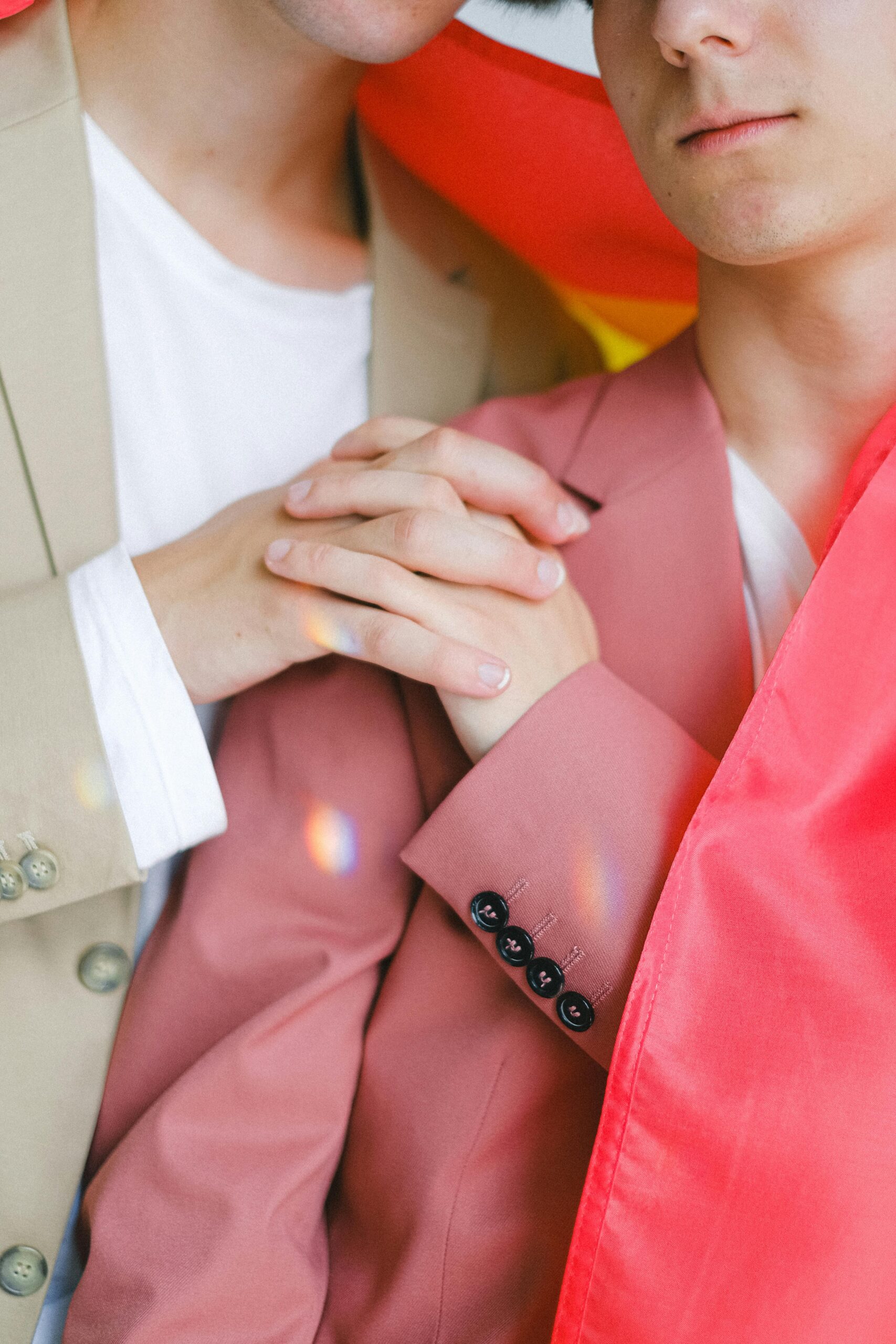 Close up image of couple holding hands on one of their shoulders.