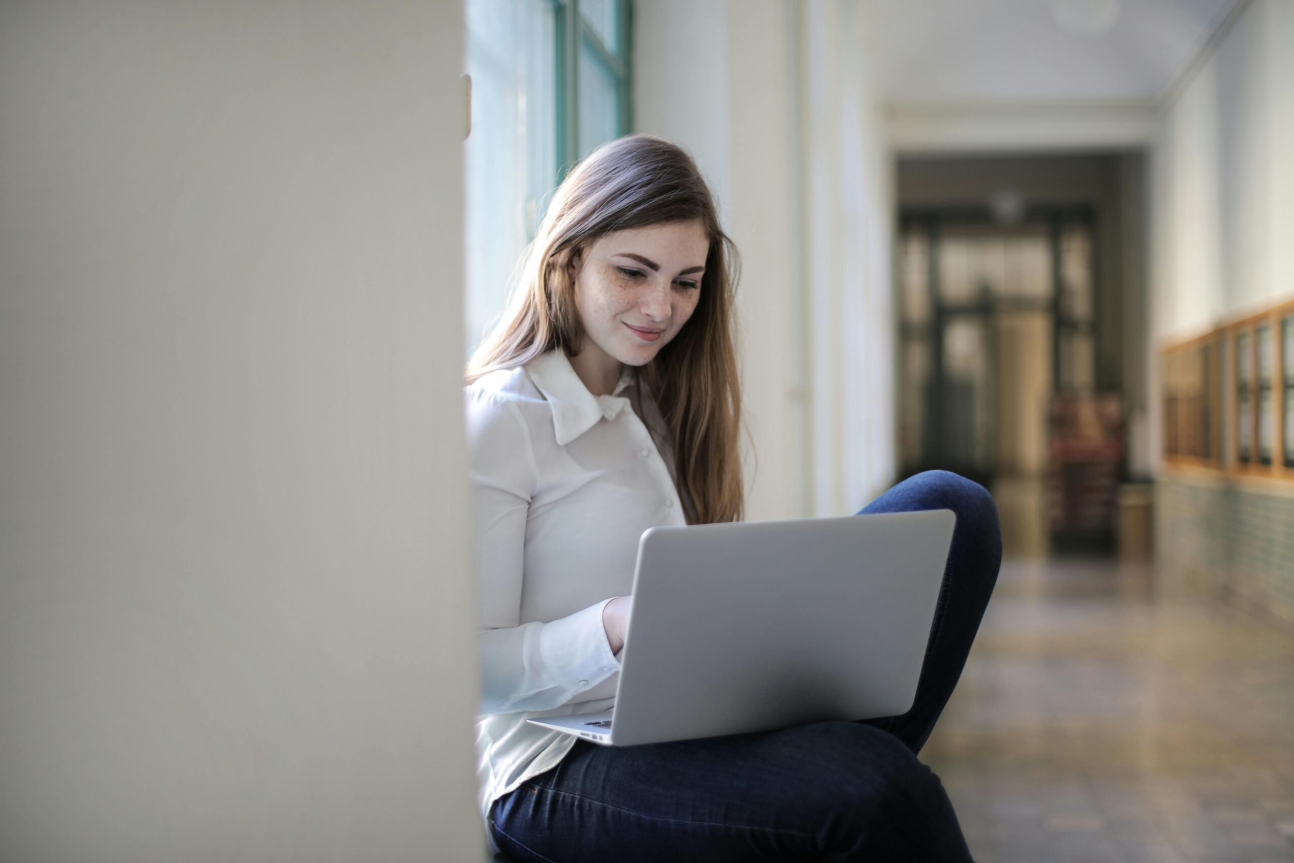 Female student studying on her computer in the hallway.