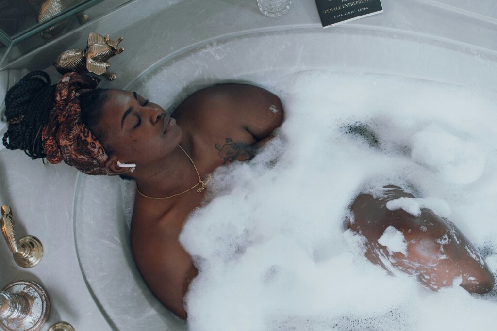 Woman relaxing in a bubble bath with headphones in.