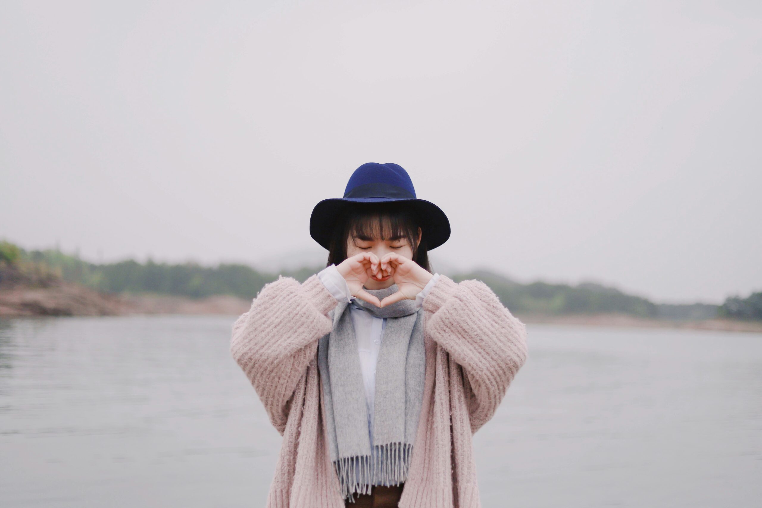 Woman outside with her hands in a heart.