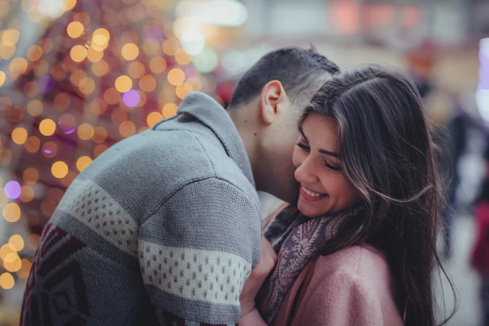 Couple smiling kissing on cheek.