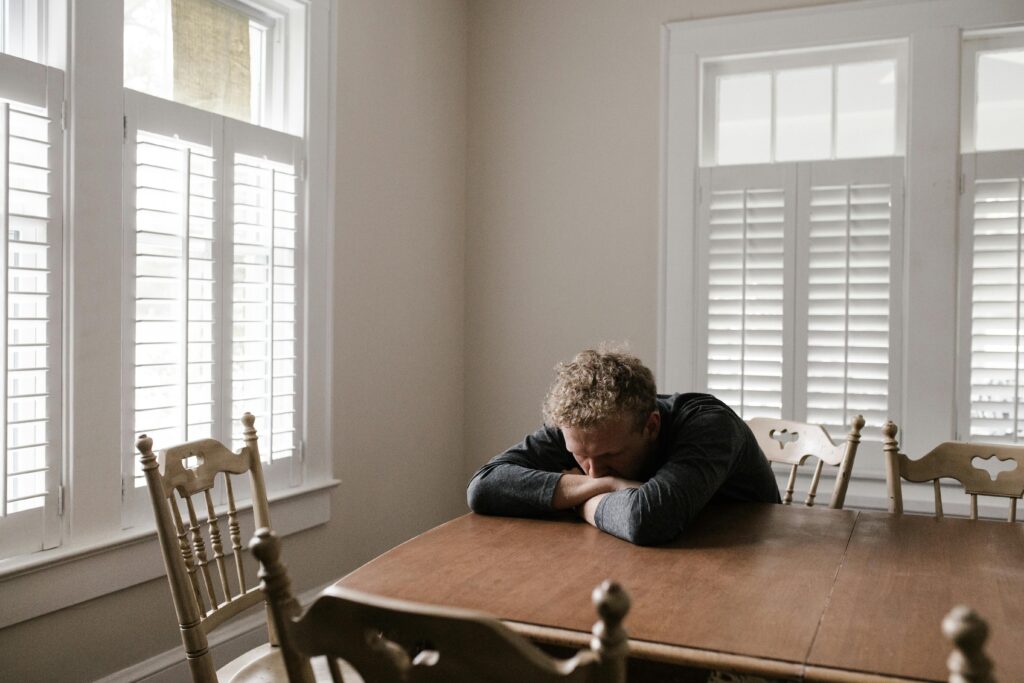 Man sitting alone laying his head down on the table.