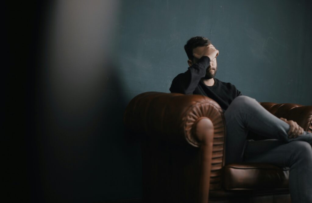 Man sitting on the couch during therapy looking stressed.
