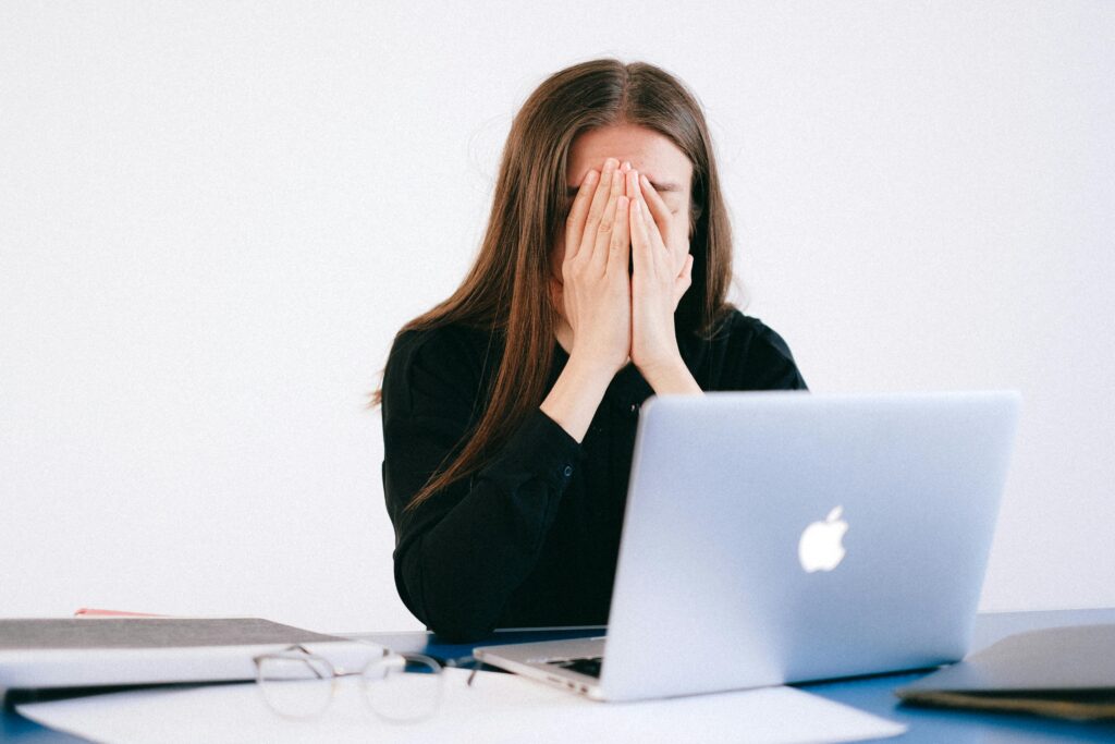 Stressed woman with her hands on her head in front of computer.