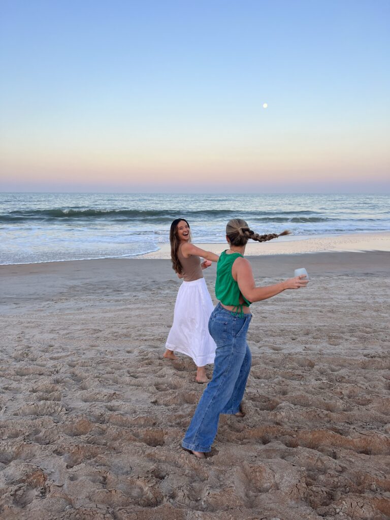 Two friends walking on the beach during sunset together.