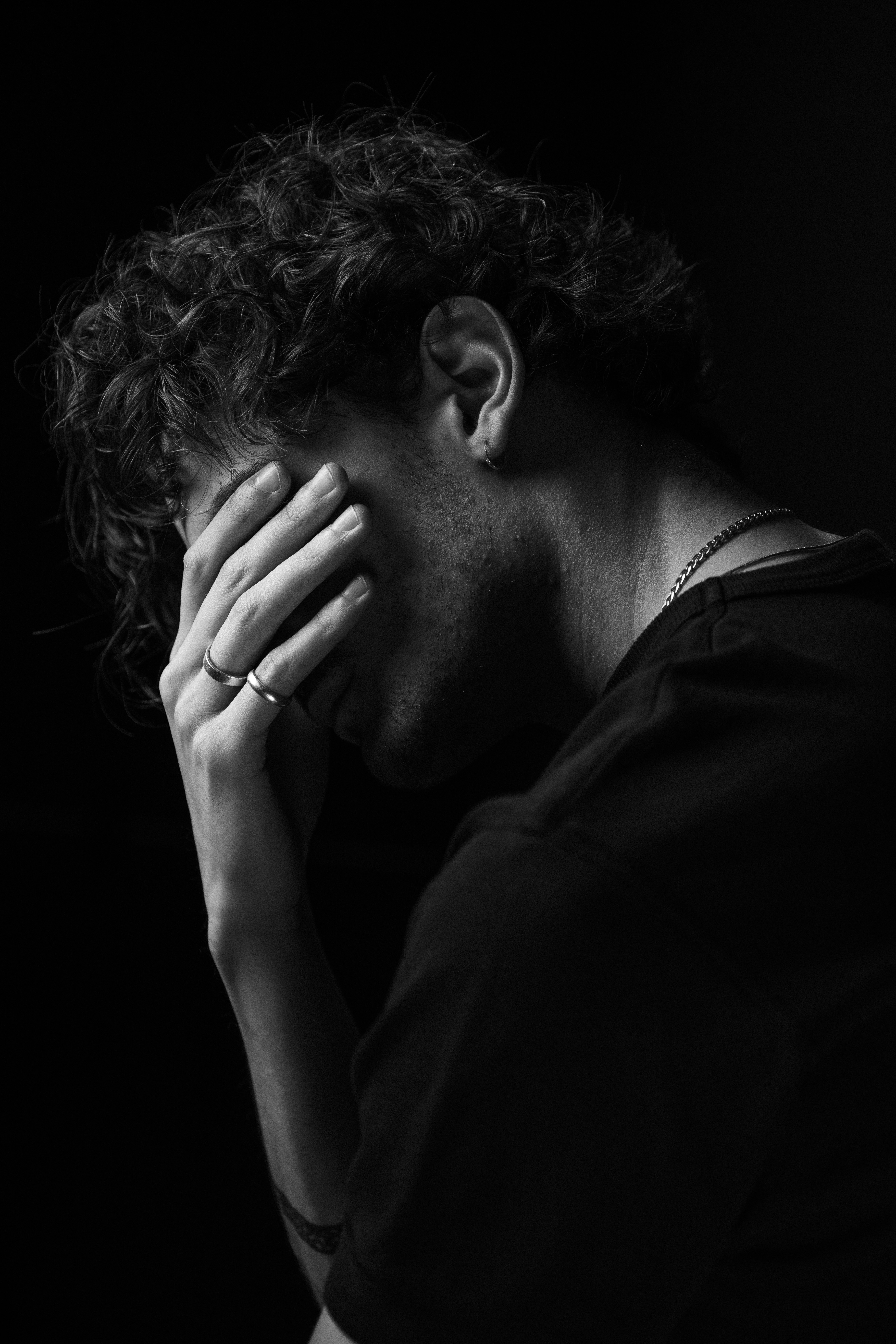 Black and white photo of anxious man covering his face with his hands.