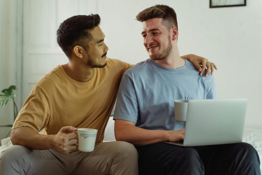 Two men holding coffee mugs looking at each other smiling.
