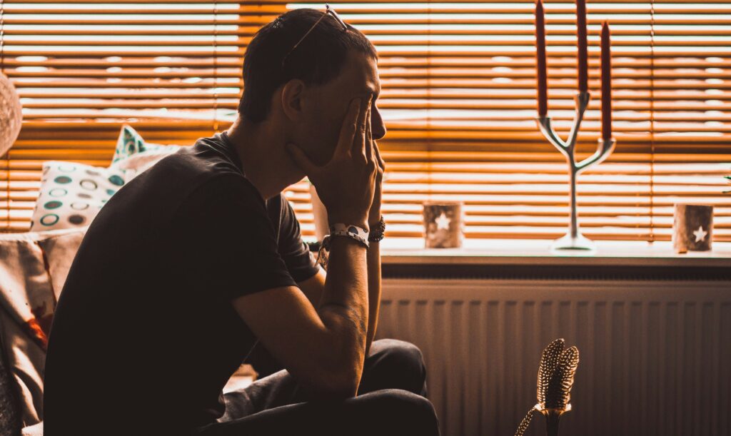 Man in therapy chair covering his eyes.