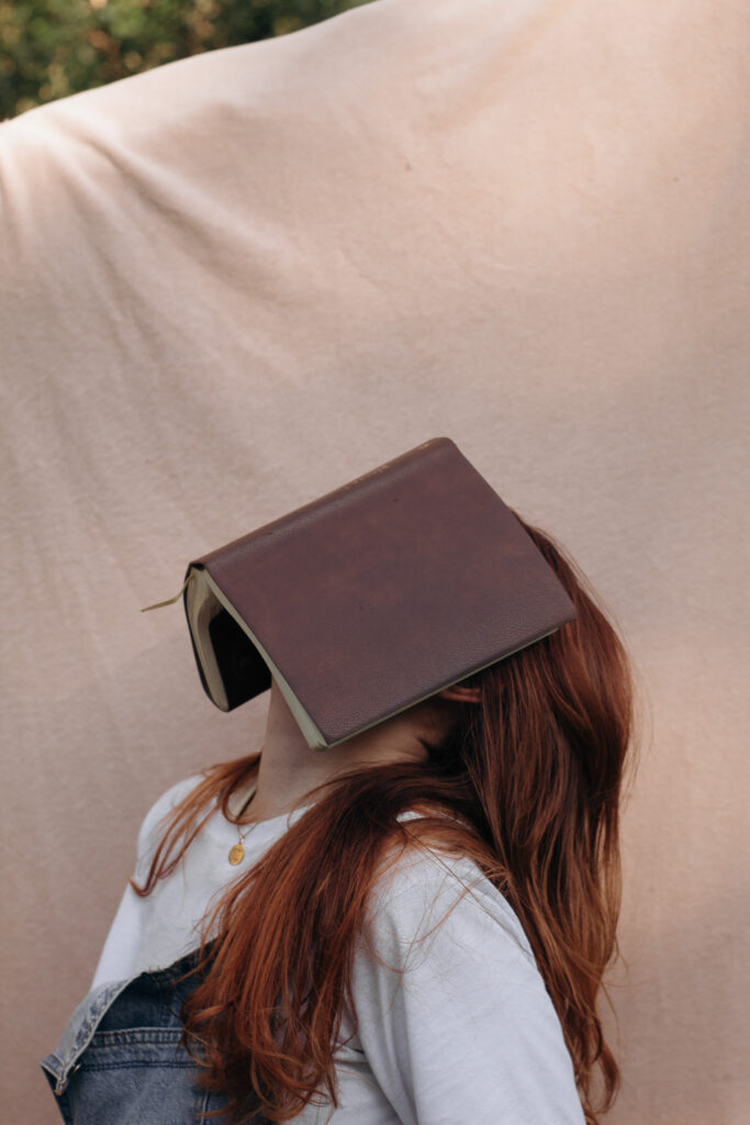 Woman looking up with a book on her face.