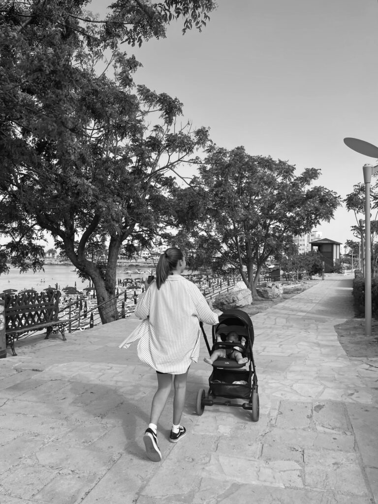 Black and white village of mom walking child in stroller outside.