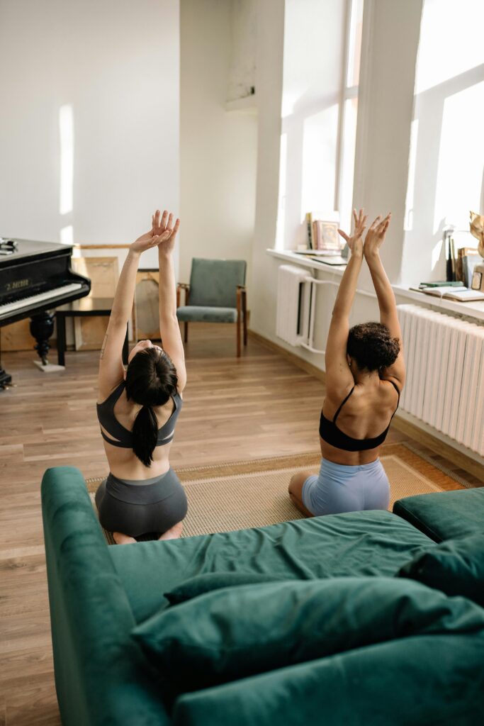Two female friends doing yoga together in an apartment.