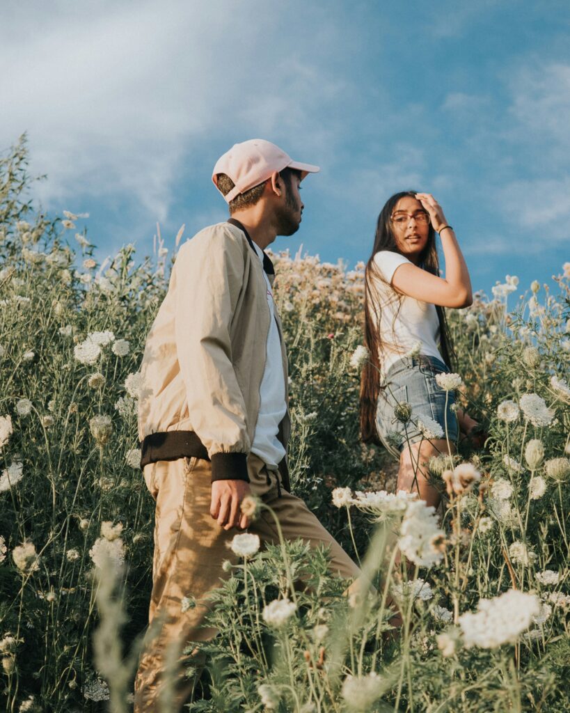 Girl and boy walking in flower field together.