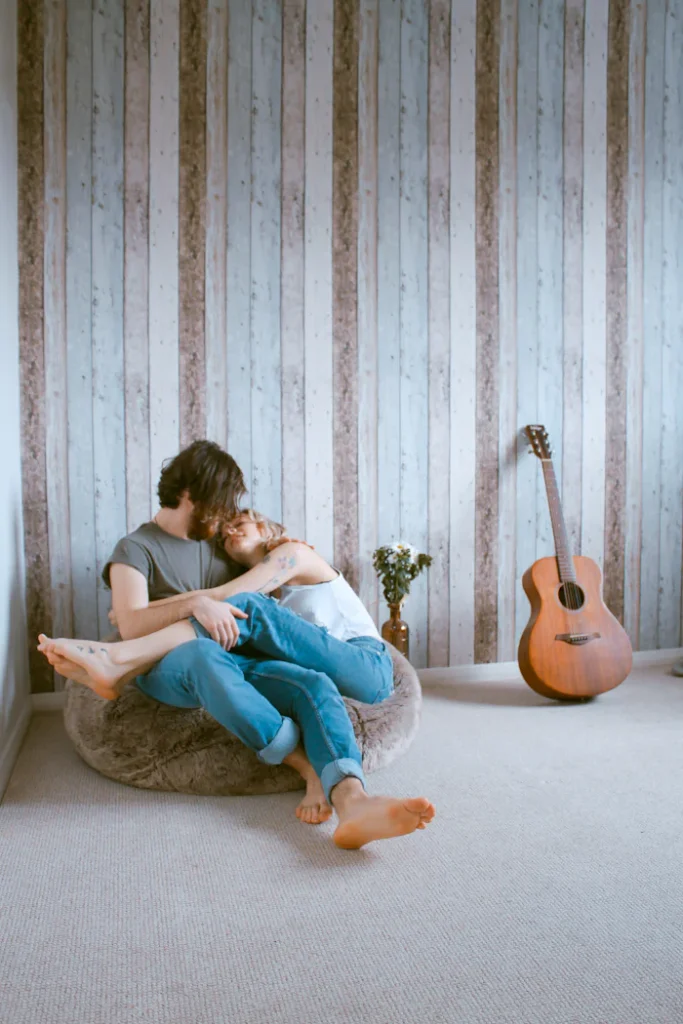 Couple sitting together cuddling on a bean bag. 