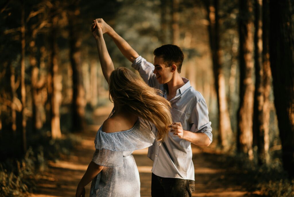 Couple dancing together in woods.