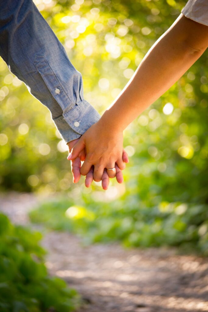 Close up of engaged couple holding hands.