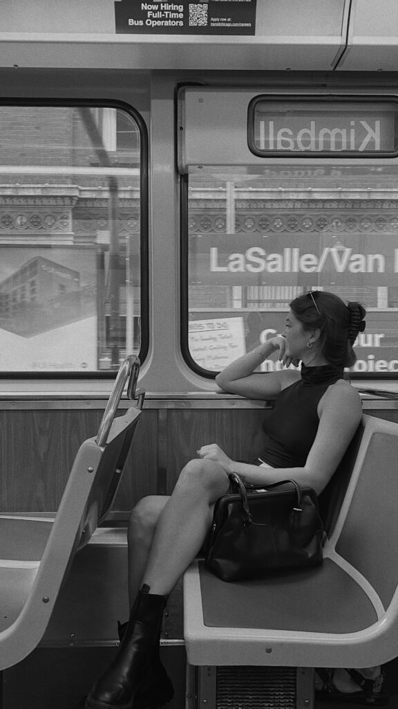 Black and white photo of girl looking out window of bus.