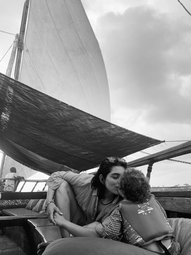 Black and white photo of mom kissing her child on a boat.