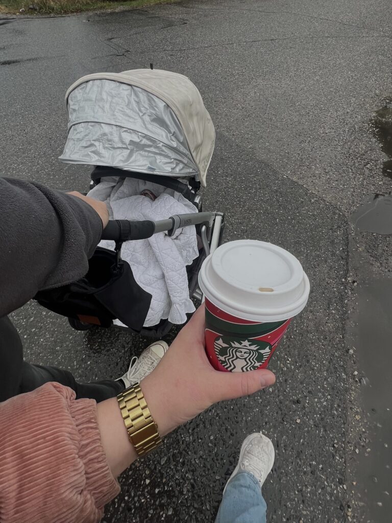 Parents walking new baby in stroller with coffee.