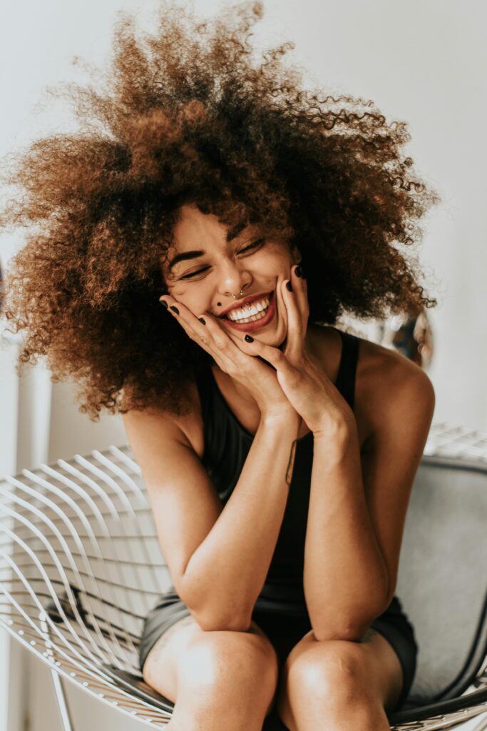 Confidence and smiling woman with her hands on her face.