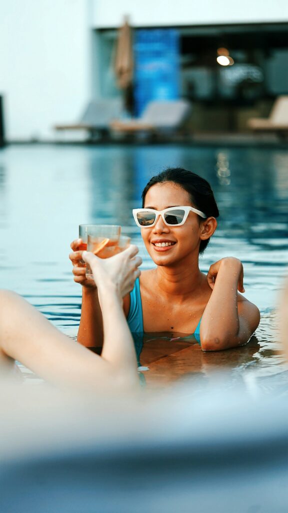 Woman in pool cheersing her drink.