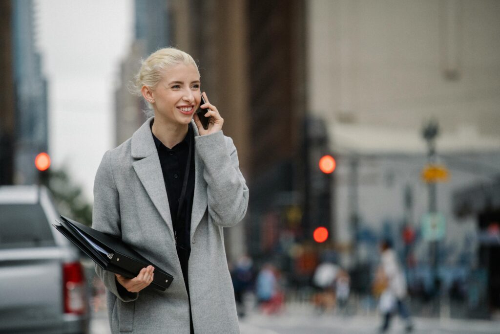 Woman smiling on her phone in the street.