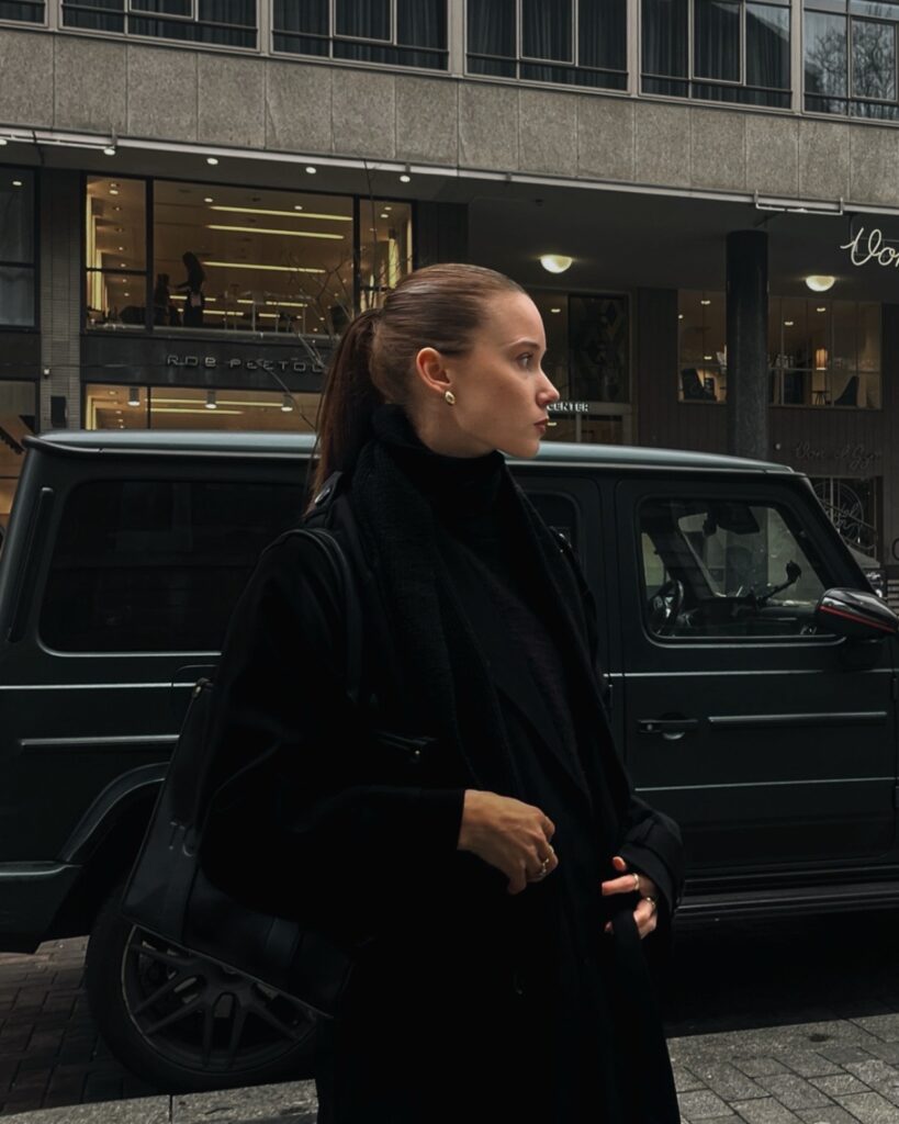 Woman on the street infront of a car alone.