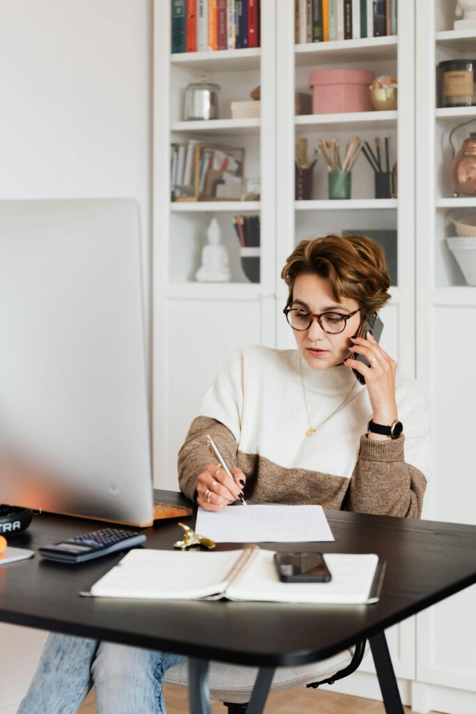 Woman working and taking notes while on the phone.