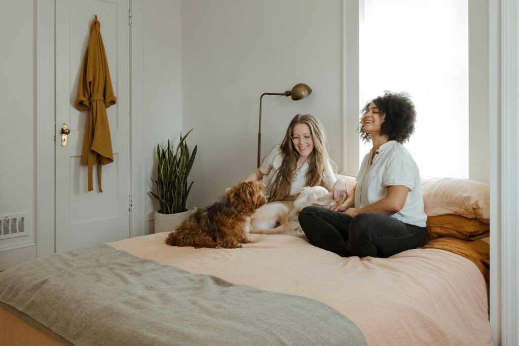 Couple sitting on their bed together with their dogs and laughing.