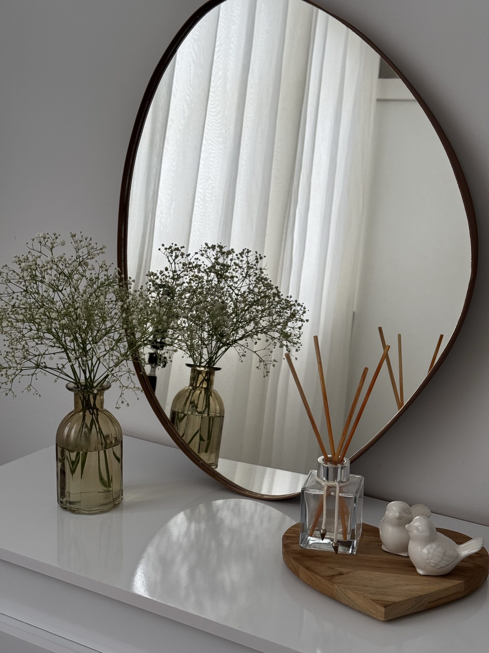 Aesthetic picture of mirror on dresser with flowers and air freshner.