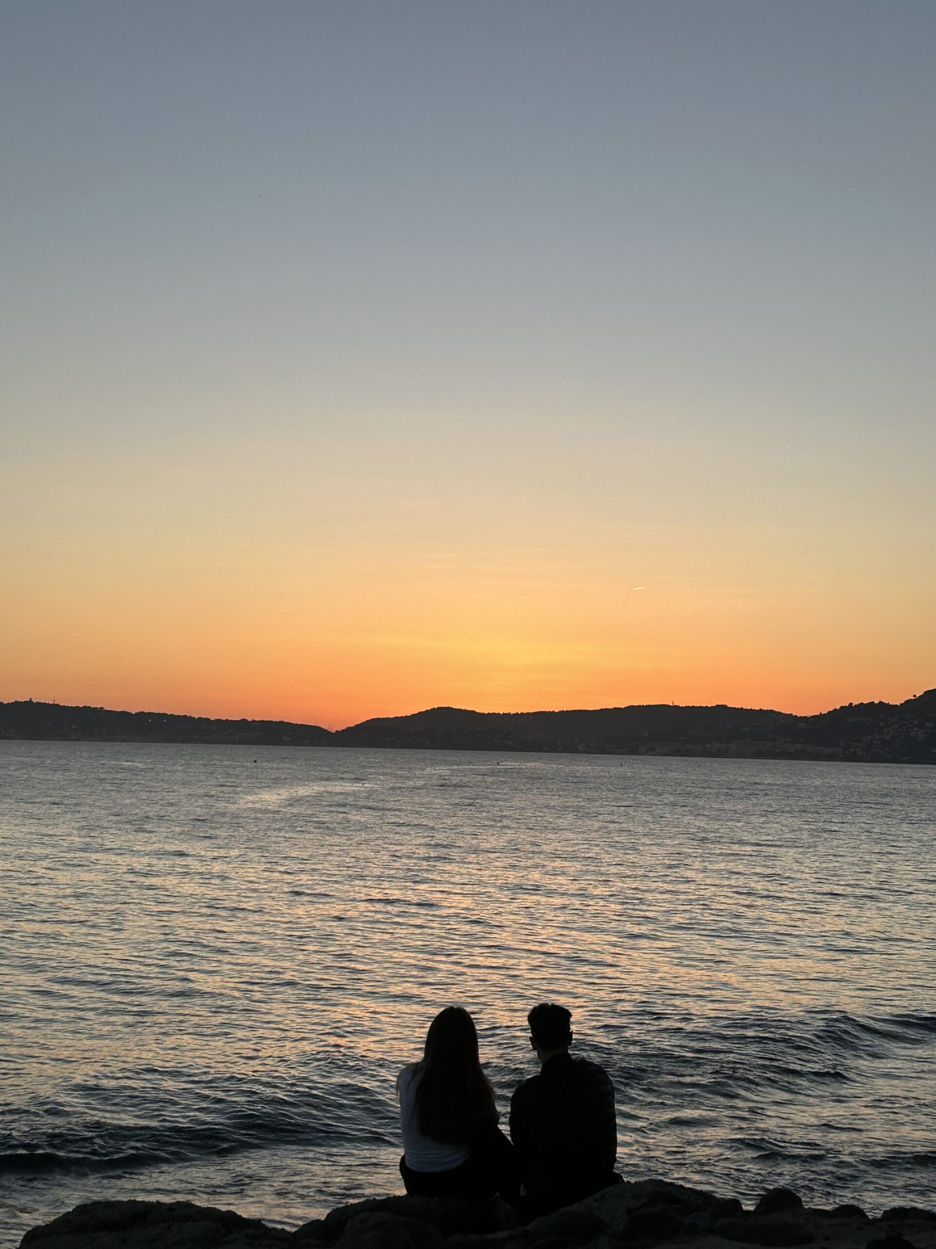 Couple sitting on the beach watching the sunset.