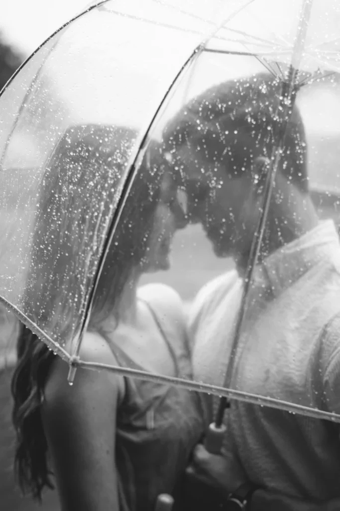Couple smiling together under umbrella. 