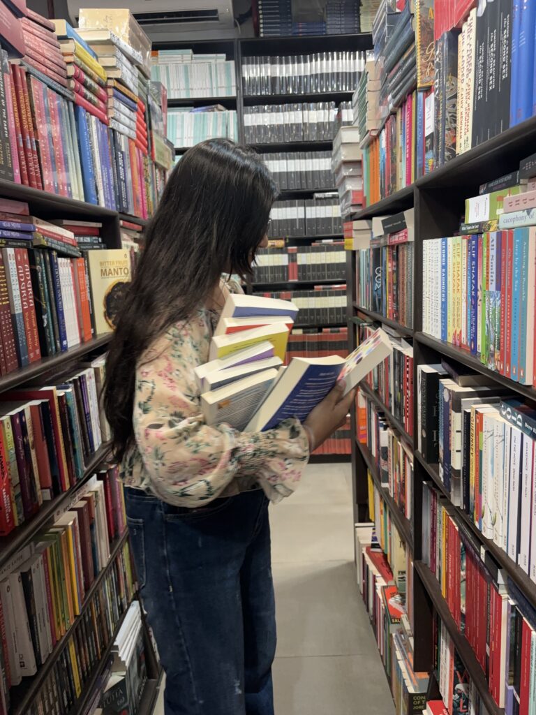Girl in library holding a bunch of books.