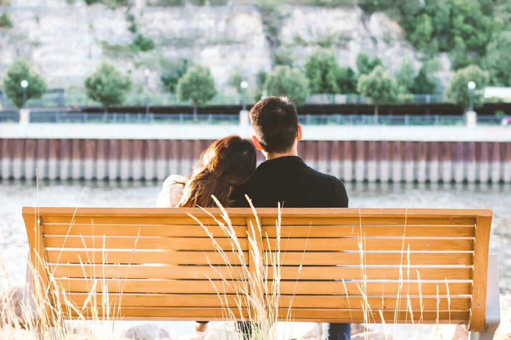 Man and woman sitting on bench looking out together. 