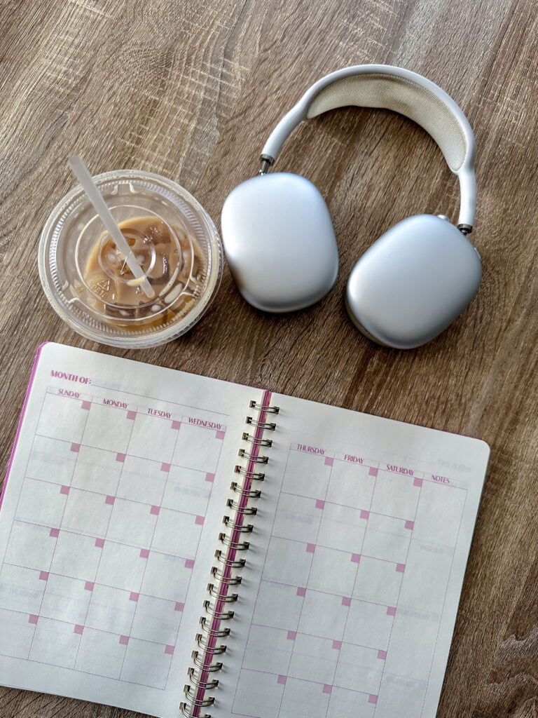Planner, coffee, and headphones on table.