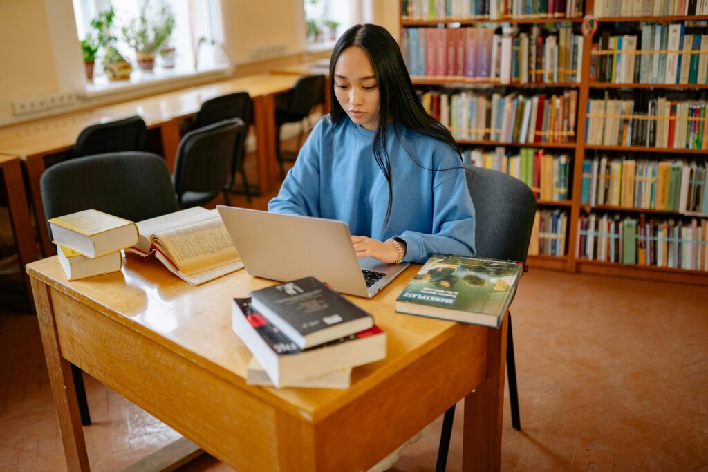 Girl doing her work in the library on her computer.