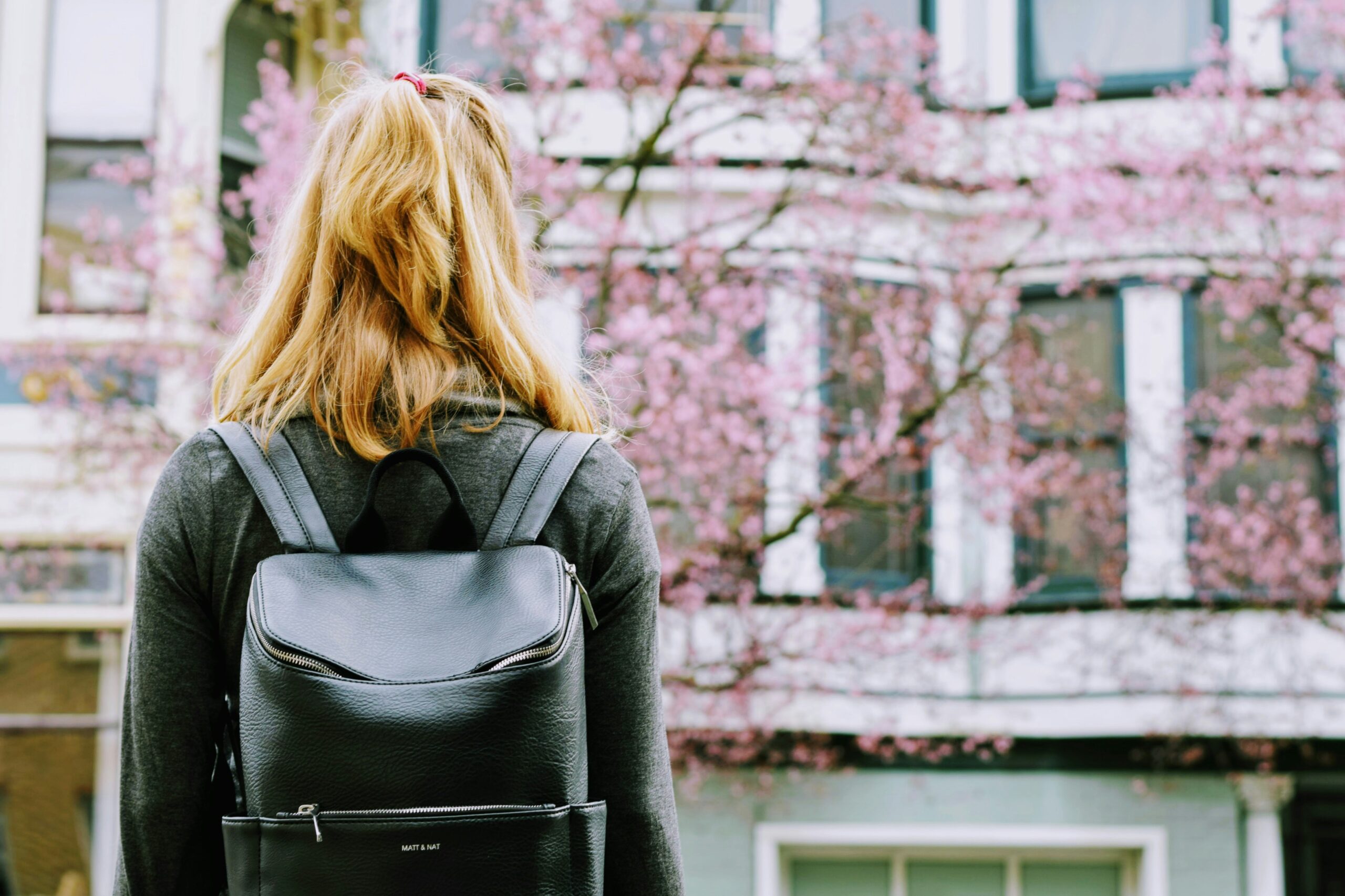 Woman standing looking at building with backpack on.