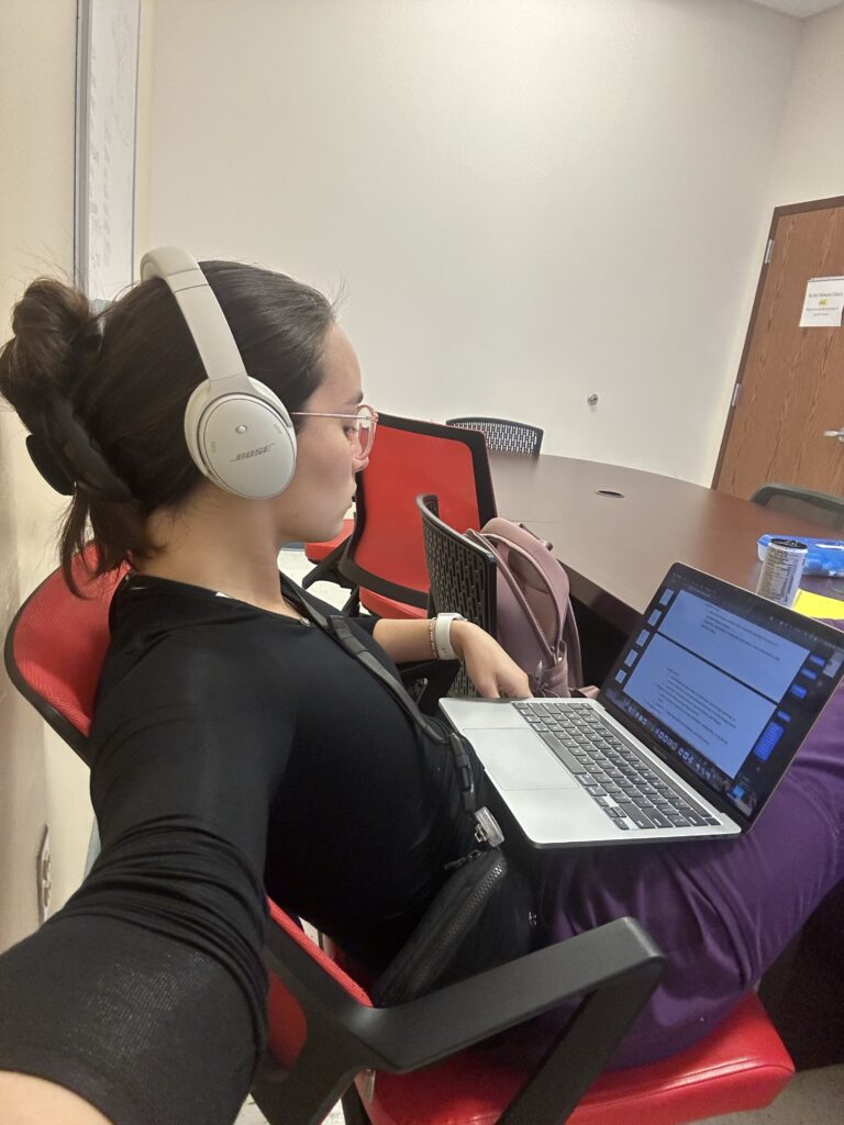 Girl studying on her computer wearing headphones.