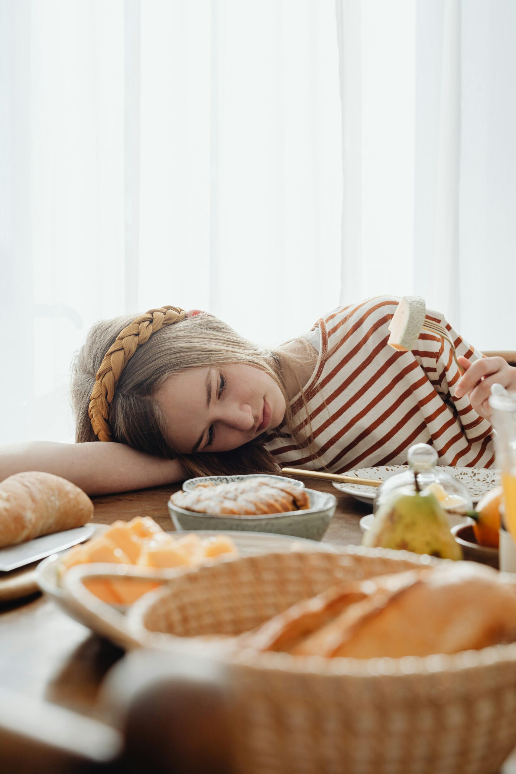 Girl with her head on the table, looking at her food.