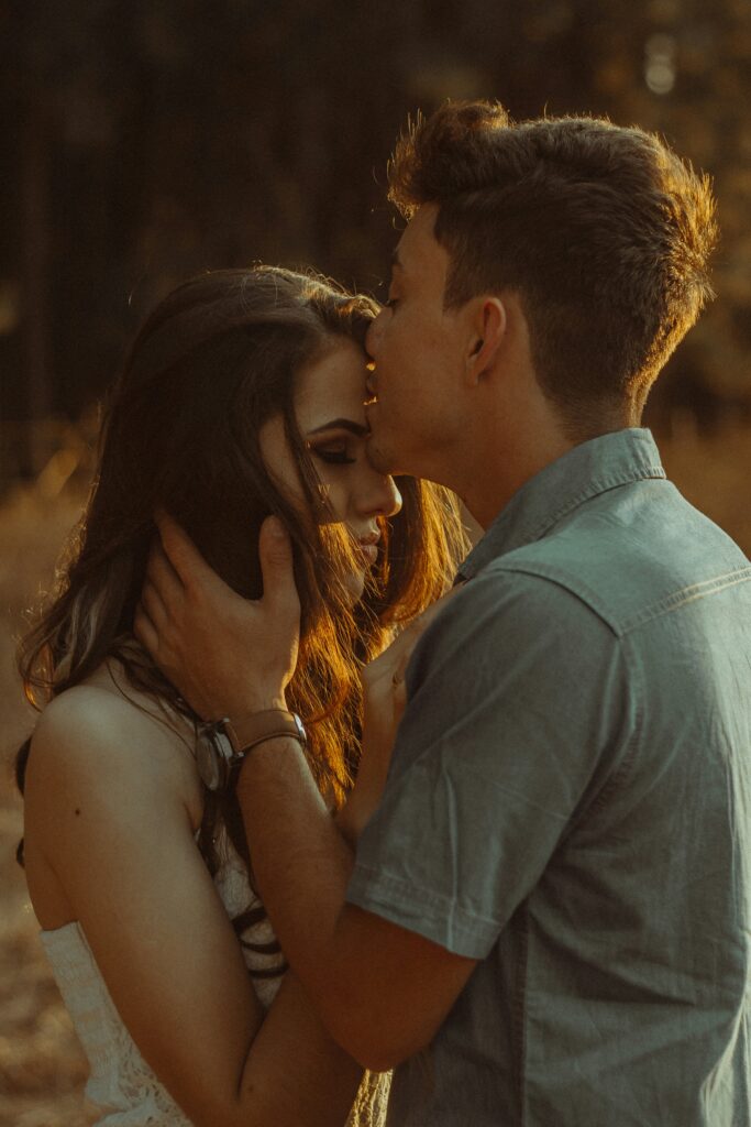 Man kissing woman's forehead and holding her face.